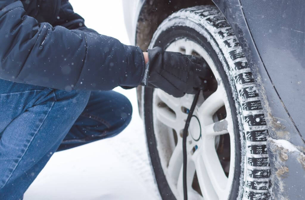 Person filling tires with air in winter.