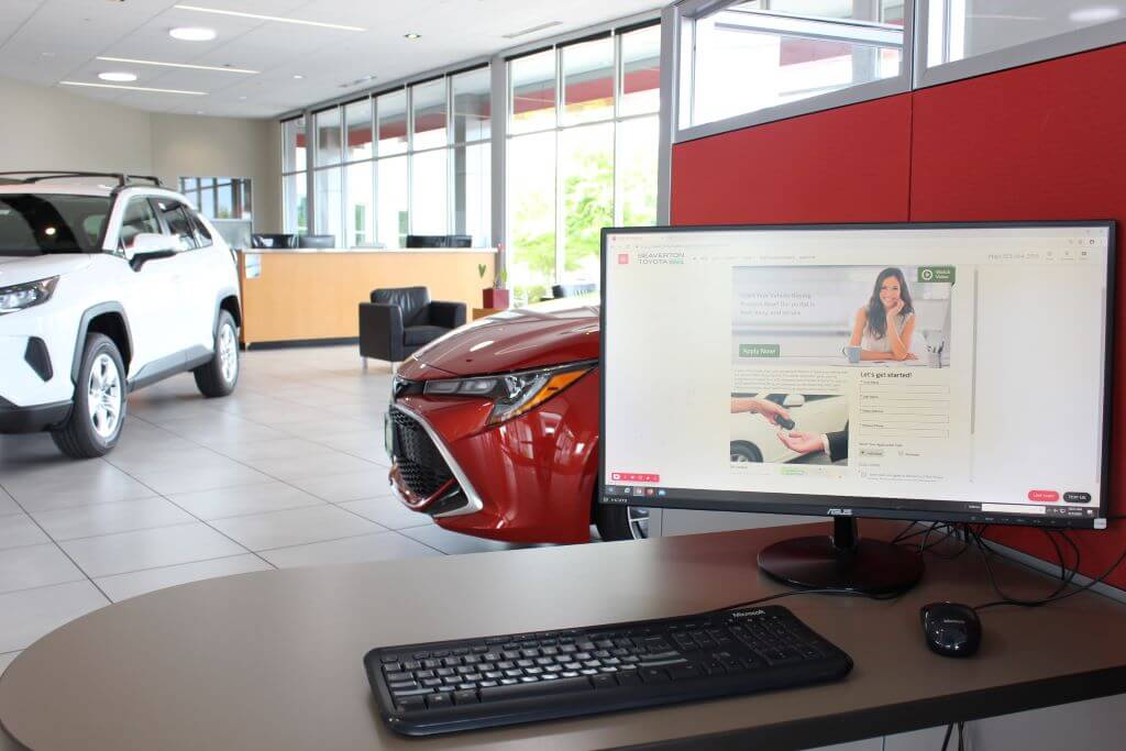 Beaverton Toyota apply for financing screen on computer with Toyota vehicles in the background.