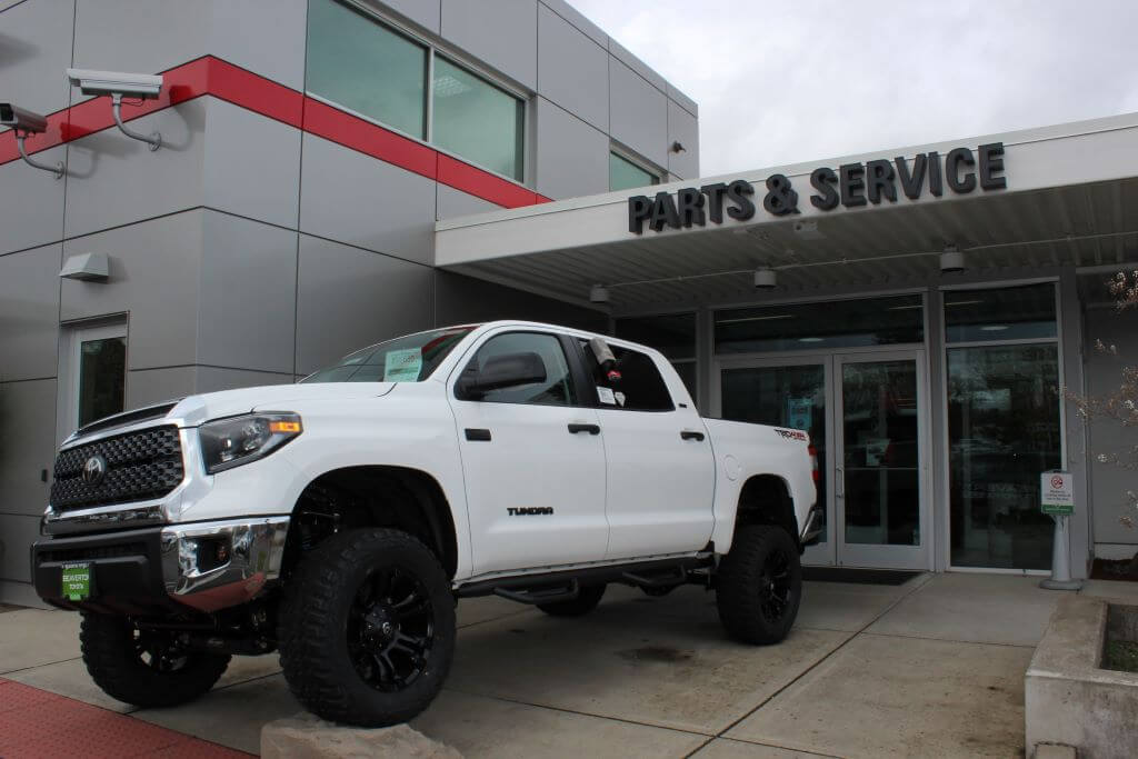 White Toyota Tundra in front of Parts & Services sign.