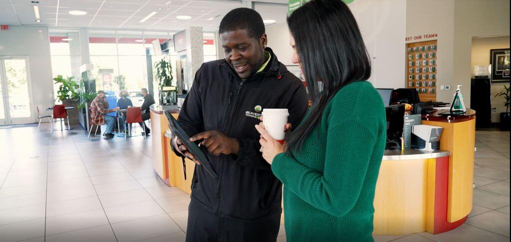 Toyota representative talking to customer, pointing to electronic tablet.